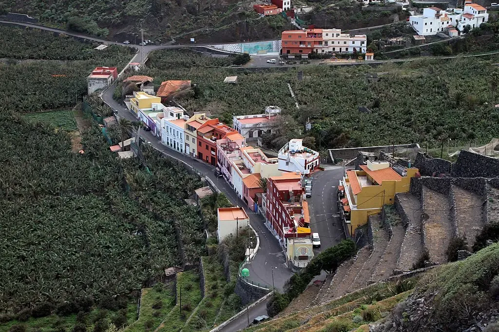 Calle estrecha y empedrada en el casco histórico de Agulo, con casas tradicionales canarias de colores y tejados rojos.