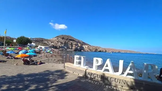 Playa de El Pajar, con barcas de pesca varadas en la arena y restaurantes cercanos