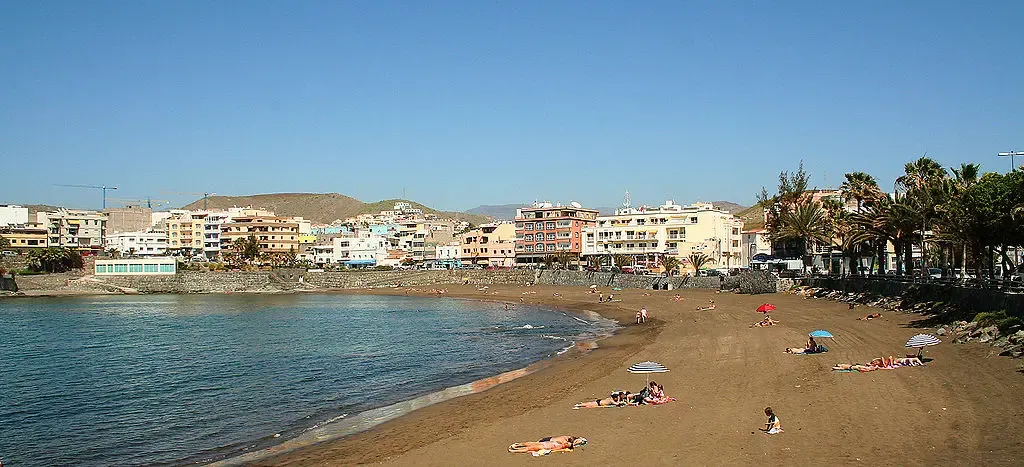 Vista aérea de la Playa de Las Marañuelas en Arguineguín, con arena oscura y aguas tranquilas