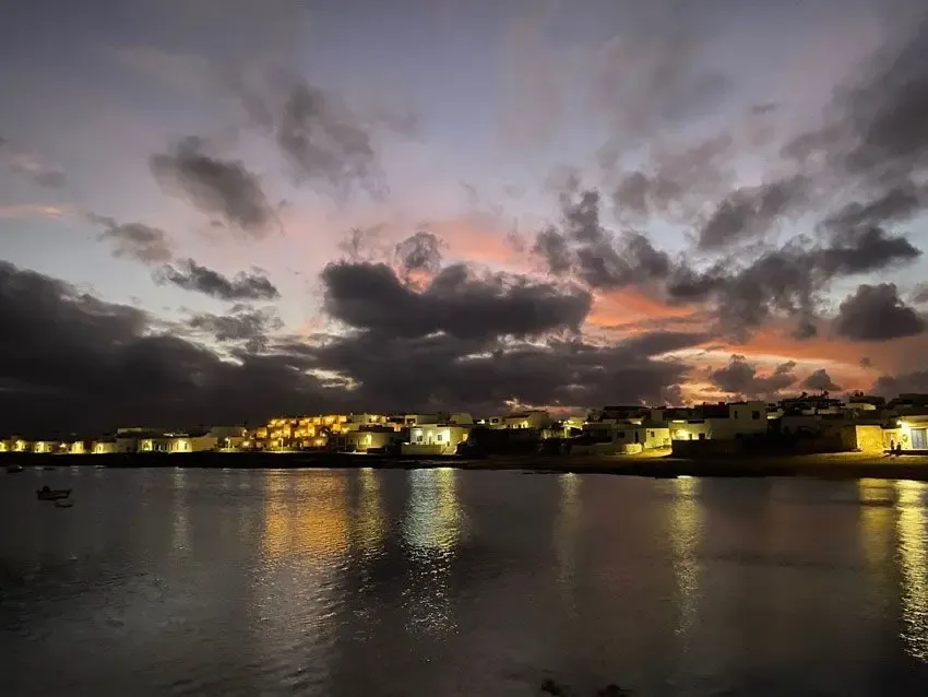Atardecer sobre el mar visto desde el muelle de Caleta de Sebo, con barcos y el Risco de Famara