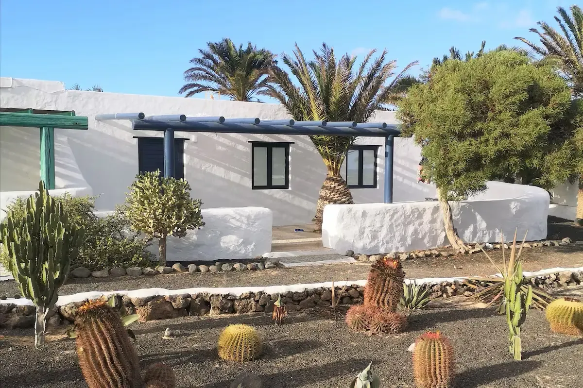 Exterior de una casa vacacional blanca y cuidada con porche en el tranquilo entorno de Pedro Barba