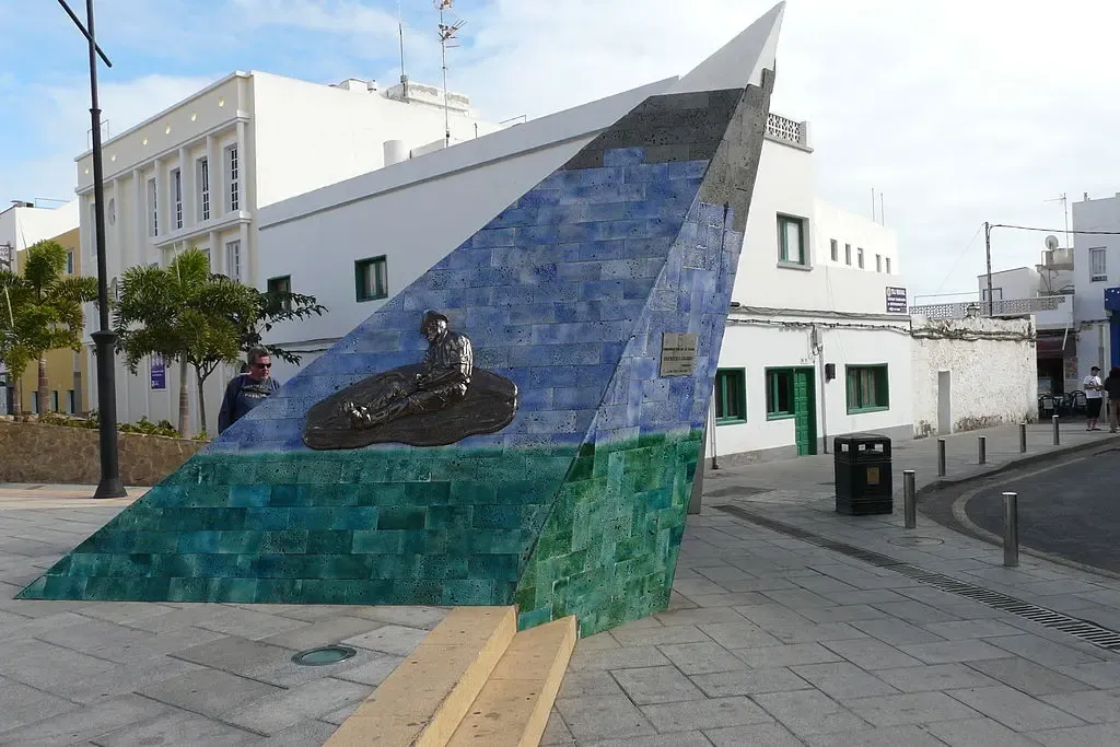 Callejón estrecho y empedrado con casas blancas y flores en el casco antiguo de Corralejo