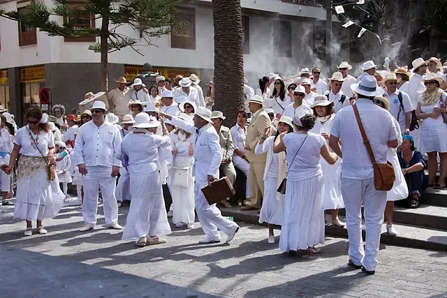 Detalle de un hombre vestido de Indiano con guayabera blanca, sombrero panamá y un puro habano.