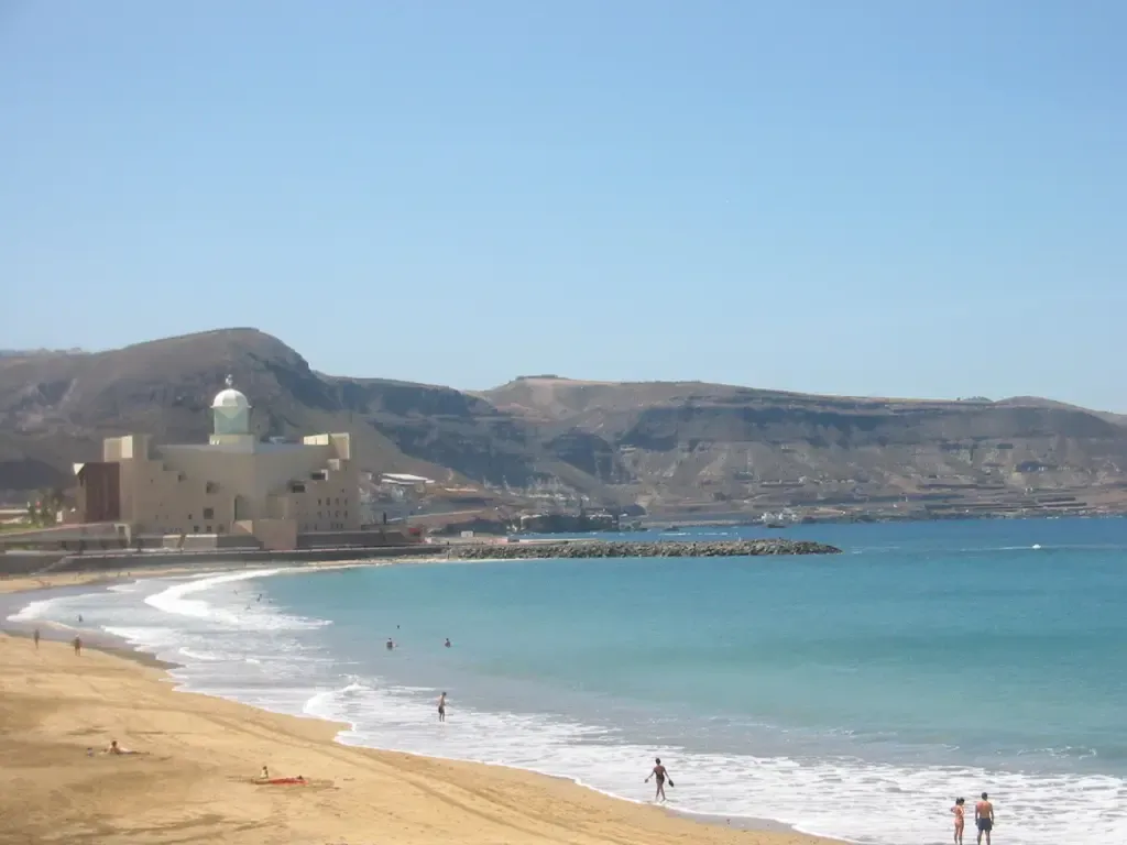 Vista de la Playa de Las Canteras en Las Palmas al atardecer, con gente paseando y La Barra visible