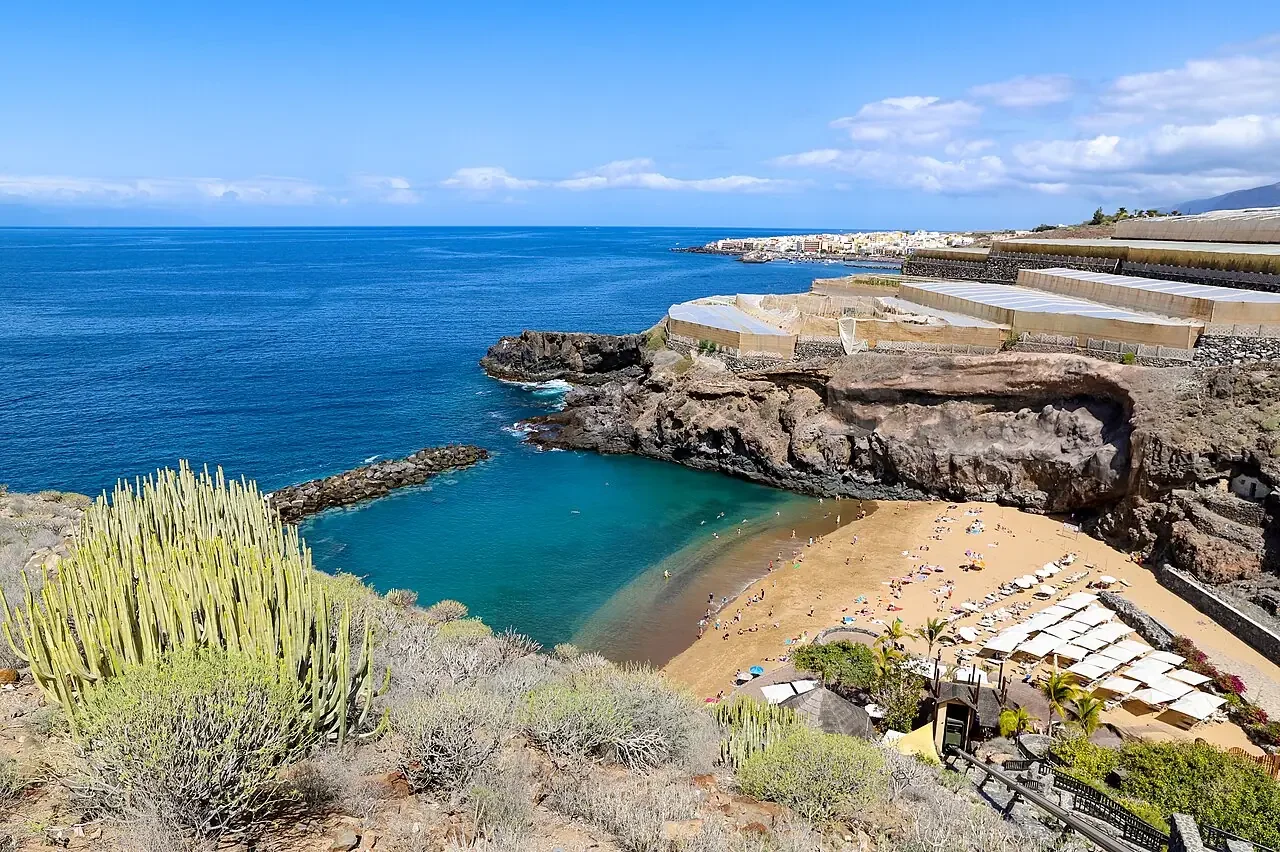 Atardecer desde la playa de Abama con la silueta de la isla de La Gomera en el horizonte y reflejos dorados en el agua.