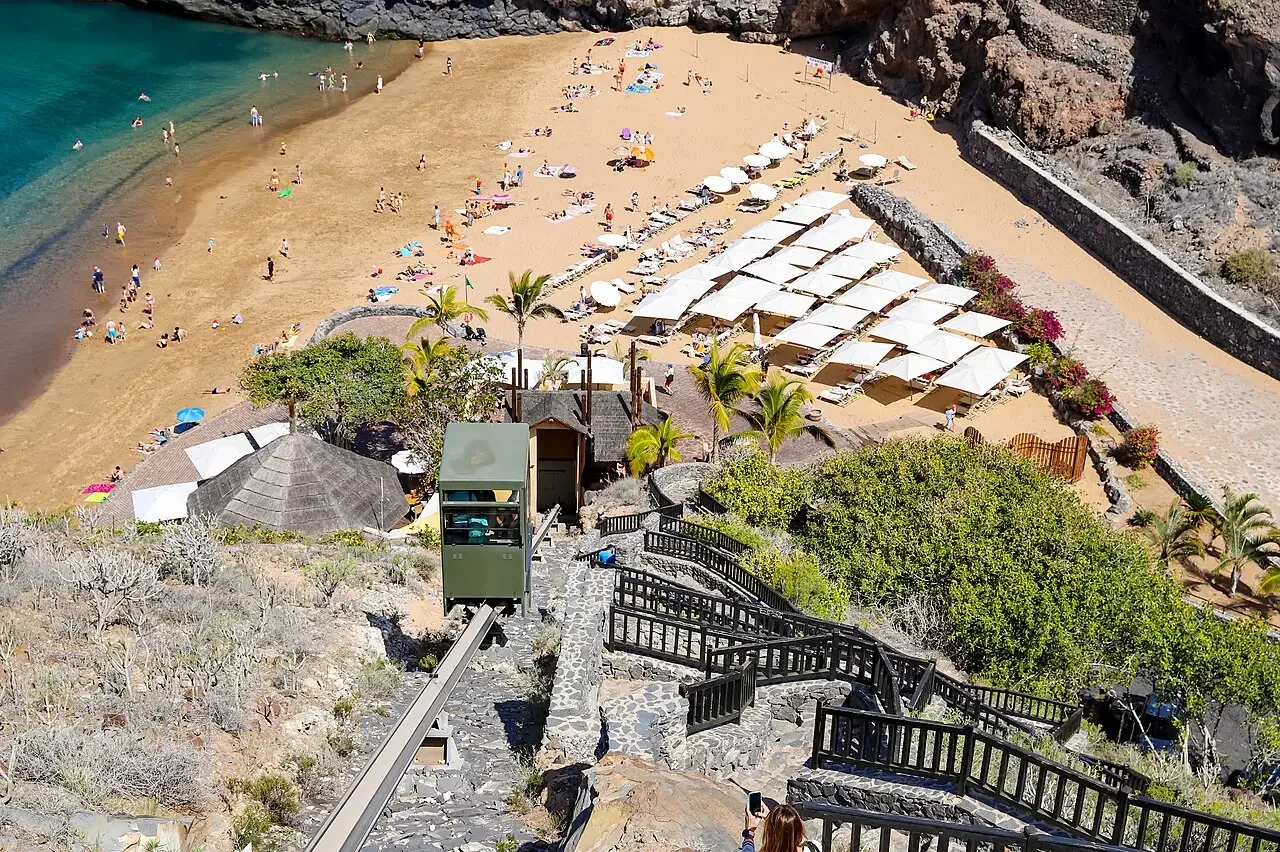 Vista panorámica de la cala de Abama en Tenerife, con su arena dorada y el acantilado cubierto de plataneras.