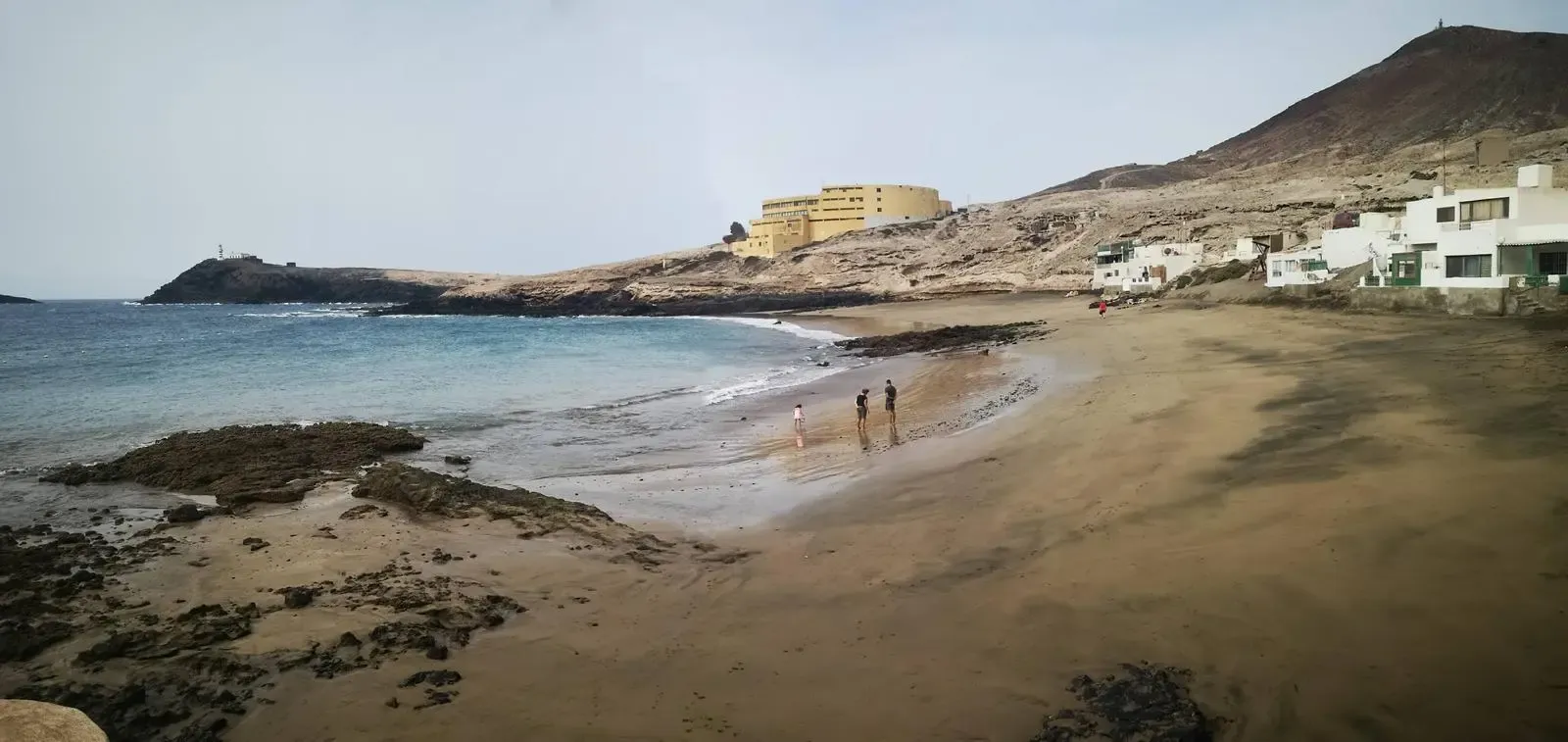 Perro explorando las rocas volcánicas en la tranquila playa de Los Cuervitos, Agüimes
