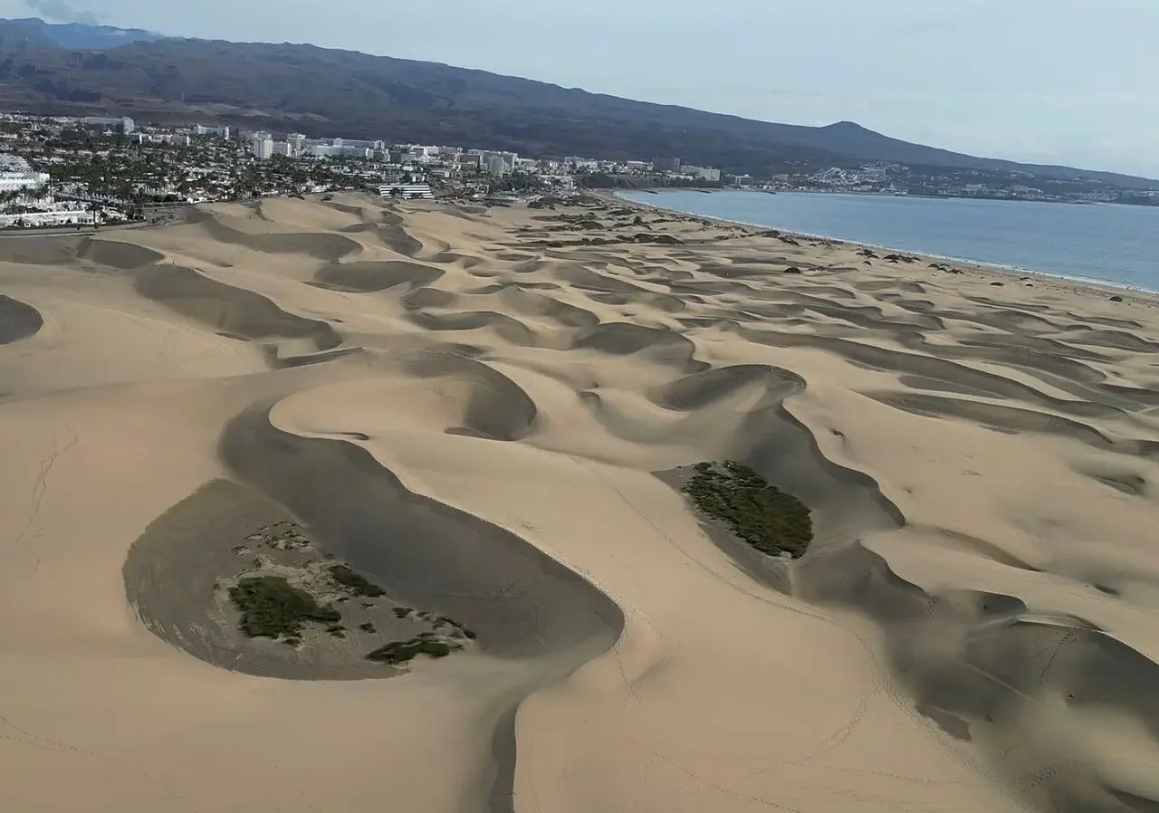 Vista de la Punta de Maspalomas donde se une con Playa del Inglés, con gente practicando deportes.